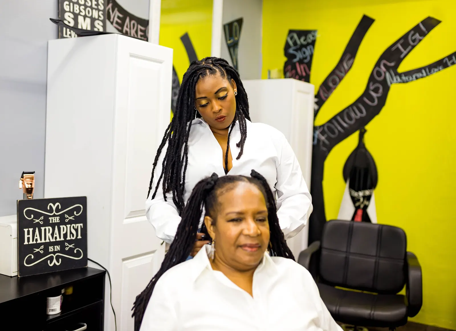 Queen styling a client's locs in the salon